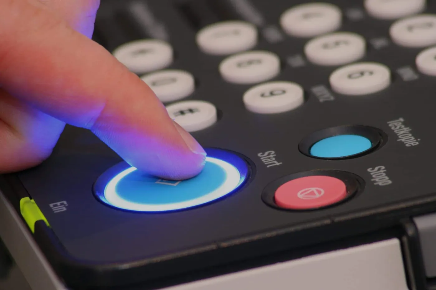 Hand pressing the start button on a photocopier control panel
